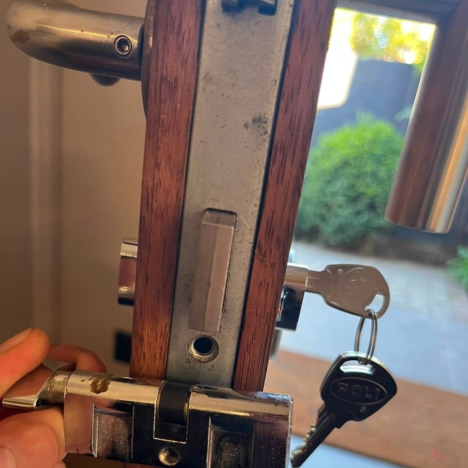 Cerradura de embutir instalada en el canto de una puerta de madera, con su llave nueva